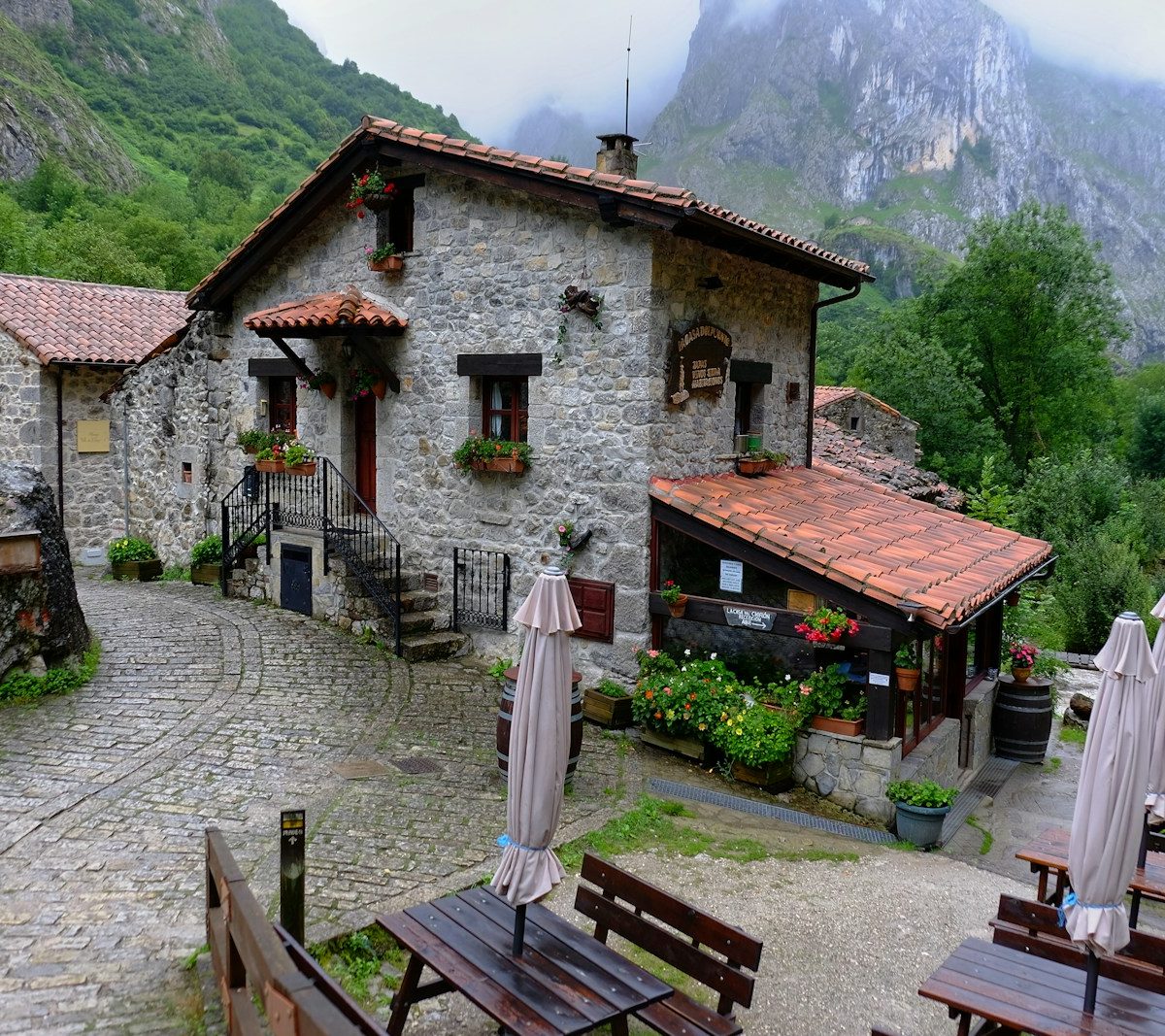 a stone building with tables and umbrellas in front of it