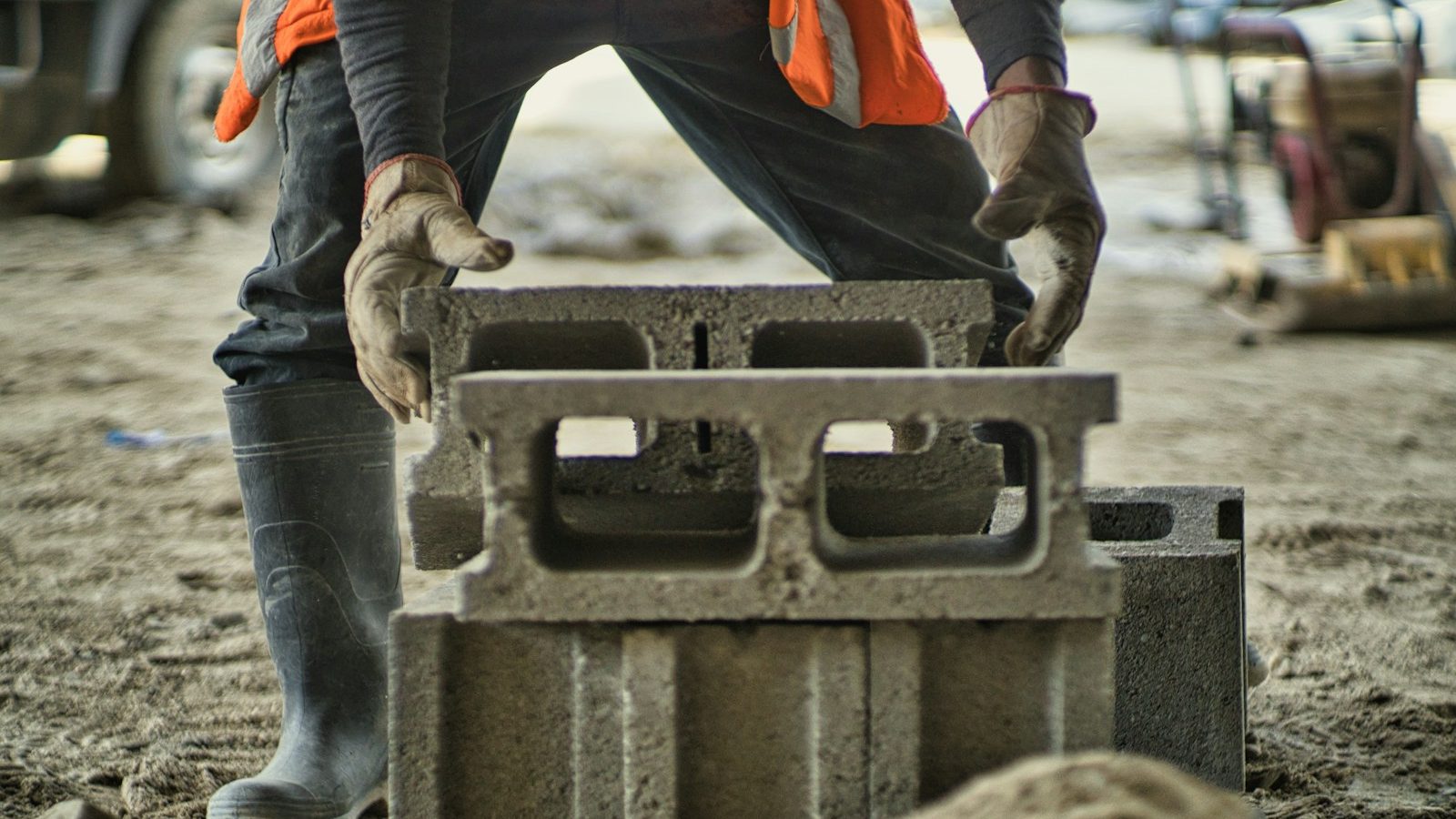 a man in an orange vest is working on a concrete block